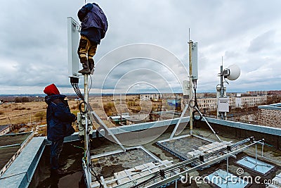 Industrial climbers -workers- without helmets, body climbing harness and uniform work at height for instaling Editorial Stock Photo