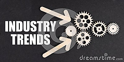 On the black surface, arrows, gears and an inscription - INDUSTRY TRENDS Stock Photo