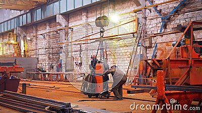 Industrial concept. A crane put down the orange detail on the floor and man worker taking it Editorial Stock Photo