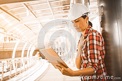 Industrial construction engineer wear safety helmet engineering working and using digital tablet on building outside. Stock Photo