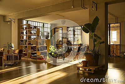 Industrial design loft, with large windows and coworking-office area. Dawn light. Interior design. Living room at home. Stock Photo