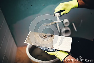 industrial detail of worker adding cement adhesive on small ceramic tiles Stock Photo