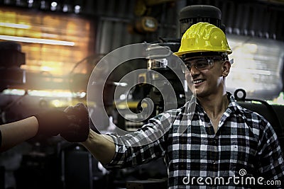 Industrial engineer wearing helmet and safe glasses, worker fist bump knuckle bump during operating with machinery at Stock Photo