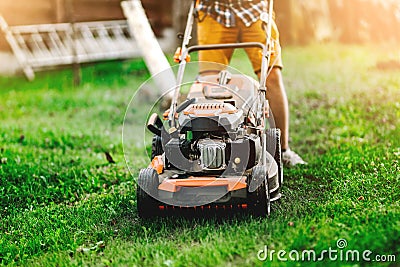 Industrial gardener working with lawnmower and cutting grass in the garden and backyard Stock Photo