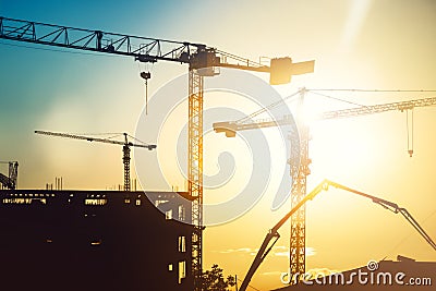 Industrial heavy duty construction site with tower cranes and building silhouettes Stock Photo