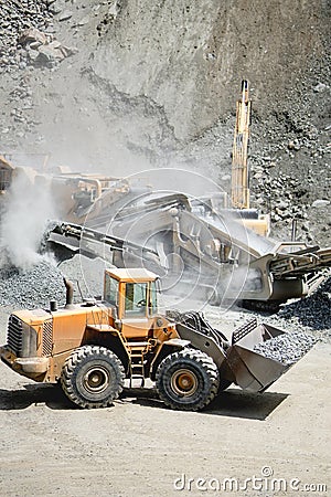 Industrial heavy duty large wheel loader moving gravel on highway construction site Stock Photo