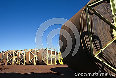 Industrial heavy duty rolls of 52 tone conveyor belts at lay down yard open field construction mine site Stock Photo