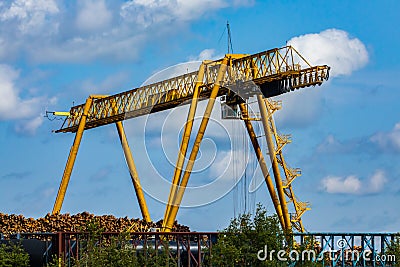 Industrial logging crane dwarfs log pile Stock Photo