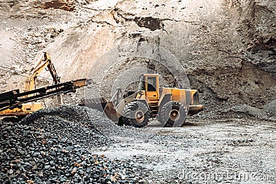 Industrial machinery on ore quarry site, heavy duty excavator moving gravel and rocks Stock Photo