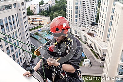 Industrial mountaineering worker hangs over residential facade Stock Photo