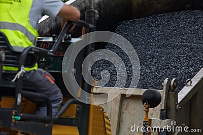 Industrial pavement machine laying fresh asphalt on road construction. Stock Photo