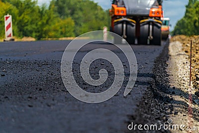 Industrial pavement truck. Laying fresh asphalt on construction site. Heavy machine industry. Mechanical engineering. Stock Photo