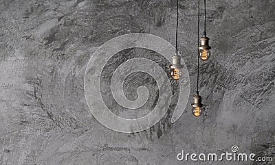 Industrial pendant lamps against a rough concrete wall. Stock Photo