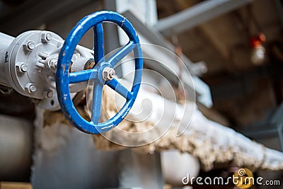 Industrial pipeline flanges blue hand wheel and valve close up, blur industrial pipelines background. Old rusty control equipment Stock Photo