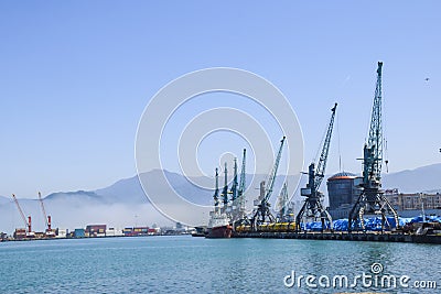 Industrial port blue water clear weather white fog on the backgroundyellow lighthouse landscape Editorial Stock Photo