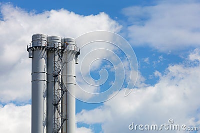Industrial round smoke-free pipes with an observation deck and a staircase against a clear blue sky with white clouds Stock Photo