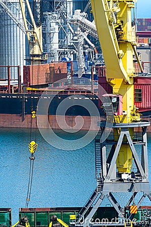 Industrial seaport infrastructure, sea, cranes and dry cargo ship, grain silo, bulk carrier vessel and grain storage elevators, Stock Photo