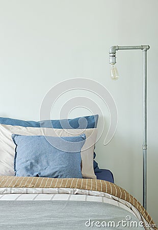 Industrial style reading lamp next to bed in blue and gray color scheme Stock Photo