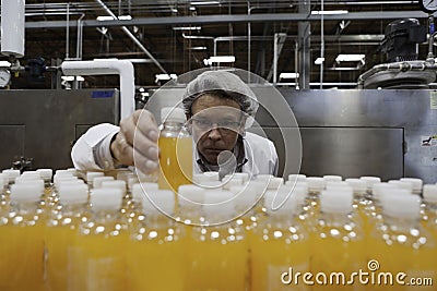Industrial worker examining bottle in factory Stock Photo