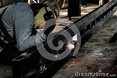 Industrial Worker at the factory welding closeup. Electric wheel grinding on steel structure in factory. Stock Photo