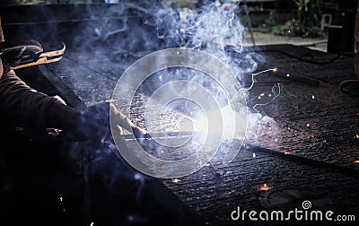 Industrial Worker at the factory welding closeup. Electric wheel grinding on steel structure in factory. Stock Photo