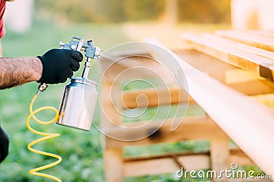 Industrial worker hand using paint gun or spray gun for applying paint on brown timber wood Stock Photo