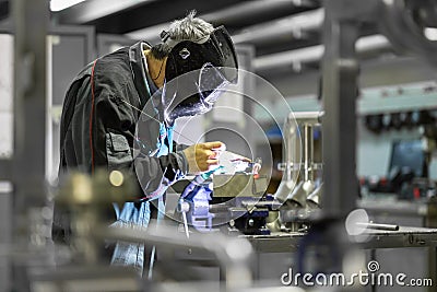 Industrial worker welding in metal factory. Stock Photo