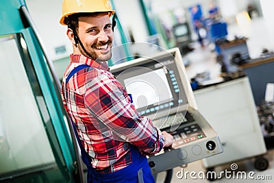 Industry Worker entering data in CNC machine at factory Stock Photo