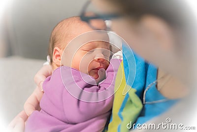 Mom holds her one month old baby girl on the shoulder while she is sleeping. Stock Photo