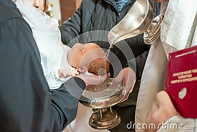Infant baptism. Baptism ceremony in Church. Water is poured on the head of an infant Stock Photo