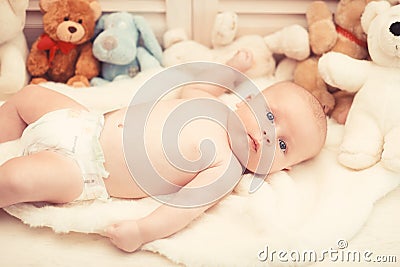 Infant with blue eyes and curious face on light blanket Stock Photo