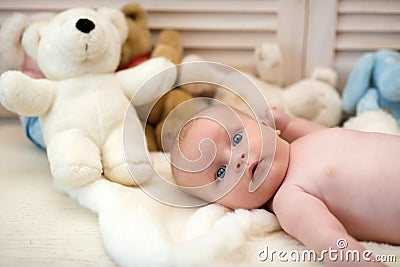 Infant with blue eyes and surprised face on light blanket Stock Photo