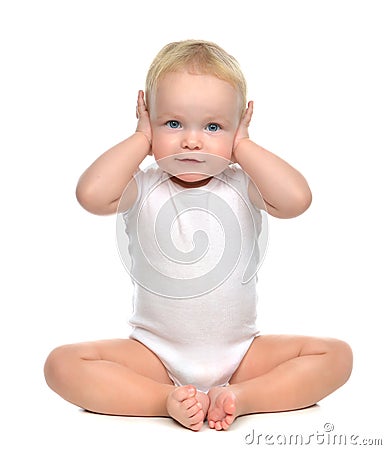 Infant child baby toddler sitting closed her hands over ears and Stock Photo