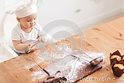 Infant cook baby portrait wearing white chef hat at kitchen table Stock Photo