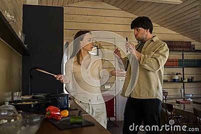 Infidelity. A jealous husband shows his cheating wife her phone, demanding an explanation, standing in the kitchen Stock Photo