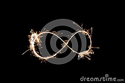 Infinity sign made with sparkler starlight dark black background bright warm isolated Stock Photo