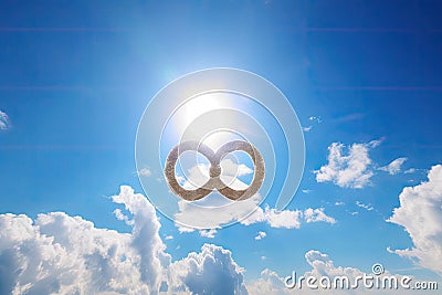 infinity sign, with sun and clouds, on a clear blue sky Stock Photo