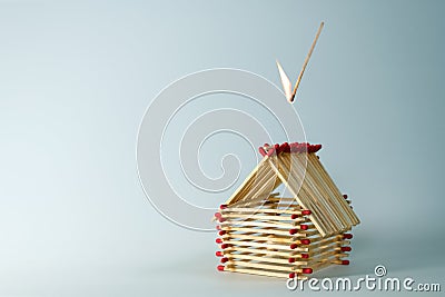 Inflamed match is falling on a house built of matches, light blue background with large copy space, insurance concept for real Stock Photo