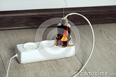 Inflamed plug in power strip indoors. Electrical short circuit Stock Photo