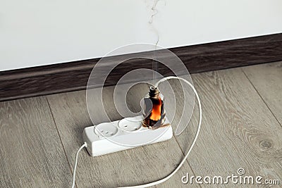 Inflamed plug in power strip indoors. Electrical short circuit Stock Photo