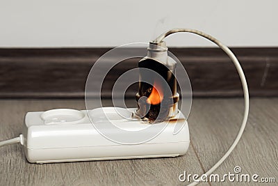 Inflamed plug in power strip indoors. Electrical short circuit Stock Photo