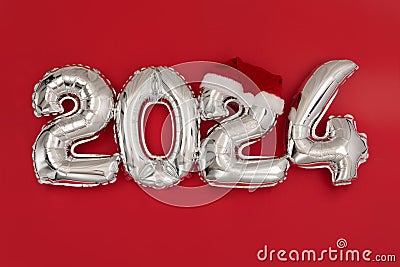 2024 inflatable balloons on red background Santa hat Stock Photo