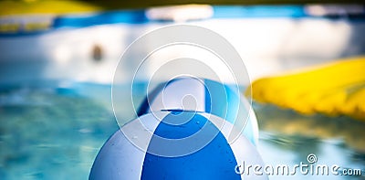 Inflatable colorful balls floating in the house garden swimming pool, with inflatable yellow mattress in the background. Strong Stock Photo