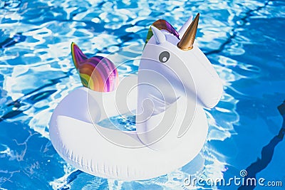 Inflatable colorful white unicorn at the swimming pool. Vacation time in the swim pool with plastic toys. Relaxation and Stock Photo