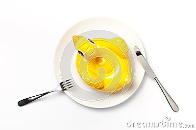 Inflatable mini yellow chicken or duckling on white plate, fork knife on white background. Creative food concept, tobacco chicken Stock Photo