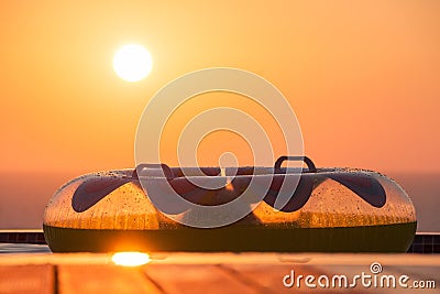 Inflatable Swim Ring on a Swimming Pool Deck overlooking Pomos sea with Sun Setting Stock Photo