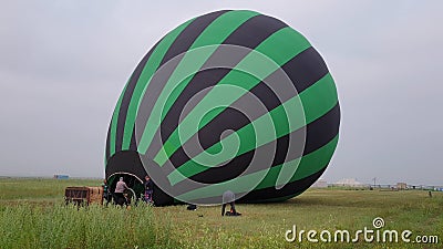 Inflating, unpack and flying up hot air balloon watermelon. Burner directing flame into envelope. Take off aircraft fly Editorial Stock Photo