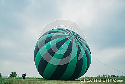 Inflating, unpack and flying up hot air balloon watermelon. Burner directing flame into envelope. Take off aircraft fly Editorial Stock Photo