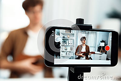 Influencer singing, playing guitar focus phone view on blur background. Gusher. Stock Photo