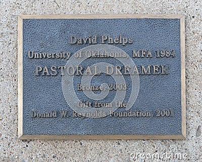 Info for `Pastoral Dreamer`, a bronze statue of a man lying in the grass on the campus of the University of Oklahoma. Editorial Stock Photo